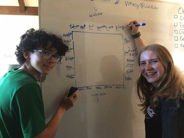 A couple of people writing on a whiteboard

Description automatically generated